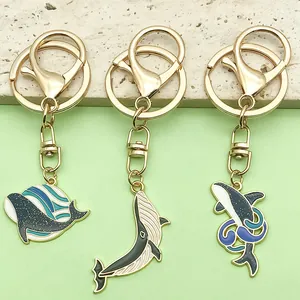 Detailed macro view of whale and dolphin enamel keychains with shiny gold metal hardware