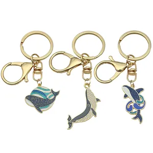 Detail of three creative enamel whale keychains with gold-toned metal and lobster clasps.