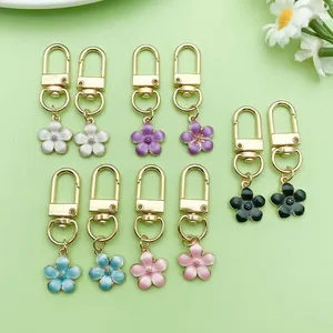 Colección de llaveros con flores de cerezo esmaltadas sobre un fondo verde claro