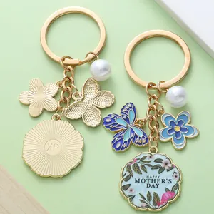 Gold-plated Mother's Day keychain with blue enamel butterfly and flower charms detail.
