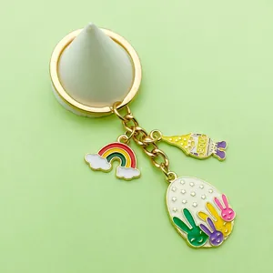 Detalle de los dijes de conejo de Pascua y arco iris en un llavero de aleación dorada
