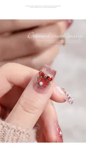 Close-up of Christmas wreath nail art jewelry with red bow and pearl on nail.
