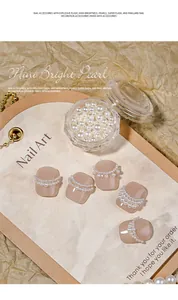 Macro detail view of mixed size high-gloss white pearls for elegant nail art decoration.
