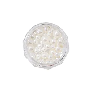 High-gloss mixed-size white nail art pearls in a clear round container