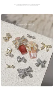 Detailed view of luxury zircon bowknot nail charms with pearl accents on a white stone background.