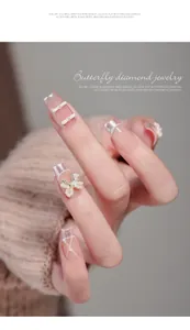Detailed view of 3D butterfly bow rhinestones and pearl nail art charms on pink nails