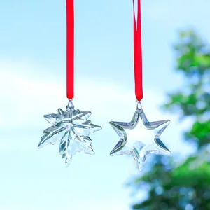Detailed view of transparent maple leaf and star suncatchers with vibrant red ribbons