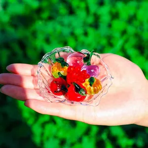 Close-up detail of miniature colorful crystal glass fruits inside a clear bowl held by hand