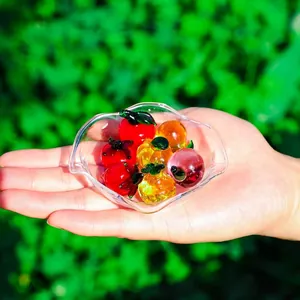 Detailed macro view of colorful miniature crystal glass fruit ornaments held in a palm