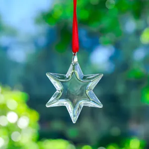 Detail of a transparent hexagram glass ornament suncatcher hanging from a red ribbon