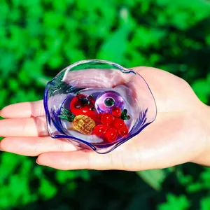 Close-up of mini crystal fruit ornaments in a small purple glass bowl held in hand