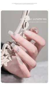 Elegante nudefarbene Maniküre mit silbernen Blattanhängern und feiner Nagelkunst