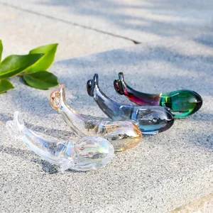 Primer plano de cuatro figuritas de ballena de cristal iridiscente en varios colores decor