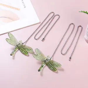 Close-up of green crystal dragonfly suncatchers with silver ball chains for garden decor