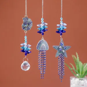 Dettaglio di acchiappasole in cristallo blu con motivi a conchiglia, medusa e stella marina.