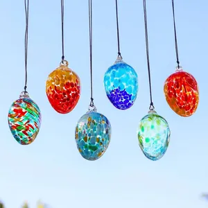 Adornos colgantes de huevos de Pascua de vidrio de colores sobre fondo de cielo
