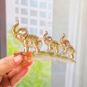 Dettaglio di tre statuine di elefanti in cristallo ambra su un piedistallo a ponte