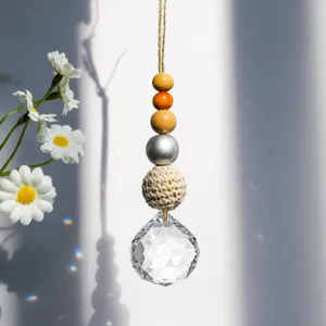 Detailed view of handmade sun catcher with wooden beads, yarn ball, and crystal prism