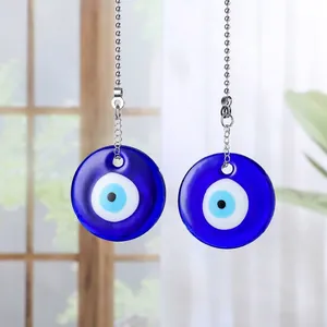 Detailed view of two blue glass evil eye pendants with silver pull chain extension