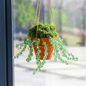 Détail du décor attrape-soleil suspendu avec perles en cristal vert et pot en terre cuite