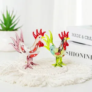 Pair of miniature glass rooster figurines with colorful patterns on a woven coaster.