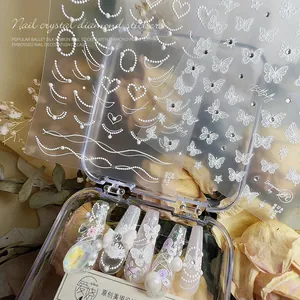 3D-reliëf nail art stickers met witte parels, kantpatronen en vlinderontwerpen.