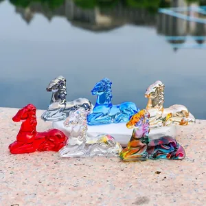 Group of six colorful crystal deer figurines displayed outdoors on a stone base