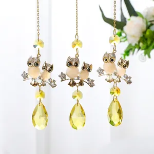 Détail de capteurs de soleil en cristal avec des hiboux dorés et des prismes jaunes