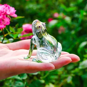 Close-up of a handcrafted iridescent glass frog figurine held in hand for scale