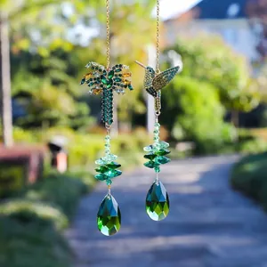 Dettaglio di acchiappasole in cristallo con disegni di colibrì e albero in un giardino