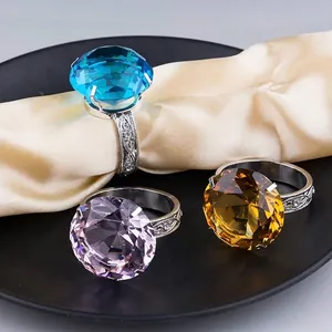 Primer plano de tres servilleteros de cristal en azul, púrpura y amarillo sobre seda.
