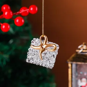 Detailed close-up view of a clear crystal gift box Christmas ornament with a shiny gold bow