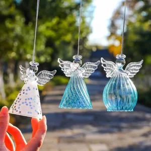 Détail de trois décorations d'anges en verre suspendues avec étoiles et textures bleues