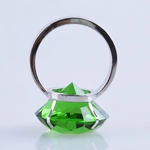 Primer plano de un gran diamante de cristal verde en un anillo de servilleta de metal plateado