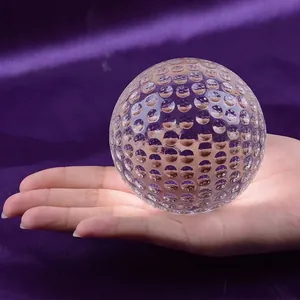 Close-up of clear K9 crystal golf ball with dimpled surface on purple background.