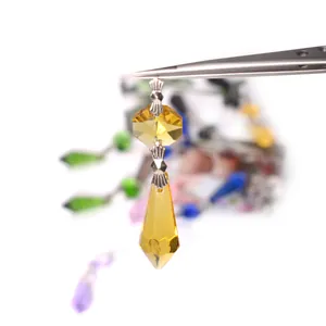 Macro view of faceted yellow crystal pendant held by tweezers for DIY lighting accessories