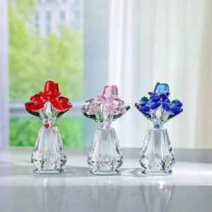 Elegante juego de tres rosas de cristal de colores en minijarrones facetados sobre mesa