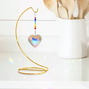 Primer plano de un atrapasol de cristal en forma de corazón en soporte dorado brillante.