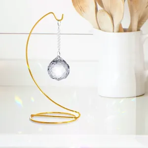 Vista detallada de una bola de cristal tallada colgada en un soporte de hierro dorado en S