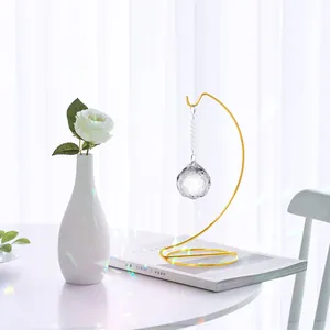 Detalle de un colgante de bola de cristal facetada en un soporte de hierro dorado en espiral