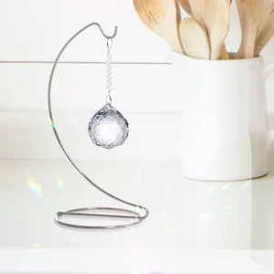 Detalle de un atrapasol de cristal facetado colgado en un soporte de hierro plateado liso