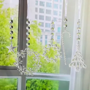 Close-up of five clear acrylic suncatcher ornaments in Christmas shapes hanging by a window