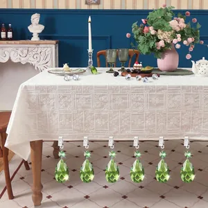 Detailed view of six green crystal teardrop tablecloth weights clipped on white lace