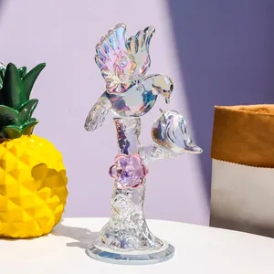 Iridescent crystal bird figurine on branch with pink flower detail