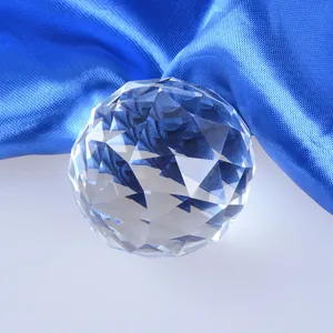 Macro view of a clear faceted crystal ball used as a photography prop on blue satin