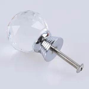 Detalle de un pomo de cristal transparente tallado con base cromada y tornillo de montaje.