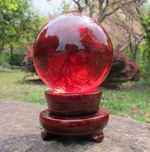 Detailed close-up view of a 10cm red transparent crystal ball on a wooden pedestal