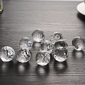 Close-up of faceted crystal glass ball pendants for lighting fixtures on a dark wooden surface.