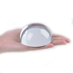 Presse-papier hémisphérique en cristal poli tenu en main sur fond blanc éclatant