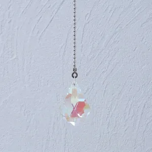 Close-up of a faceted teardrop crystal pendant with iridescent AB coating on a ball chain.